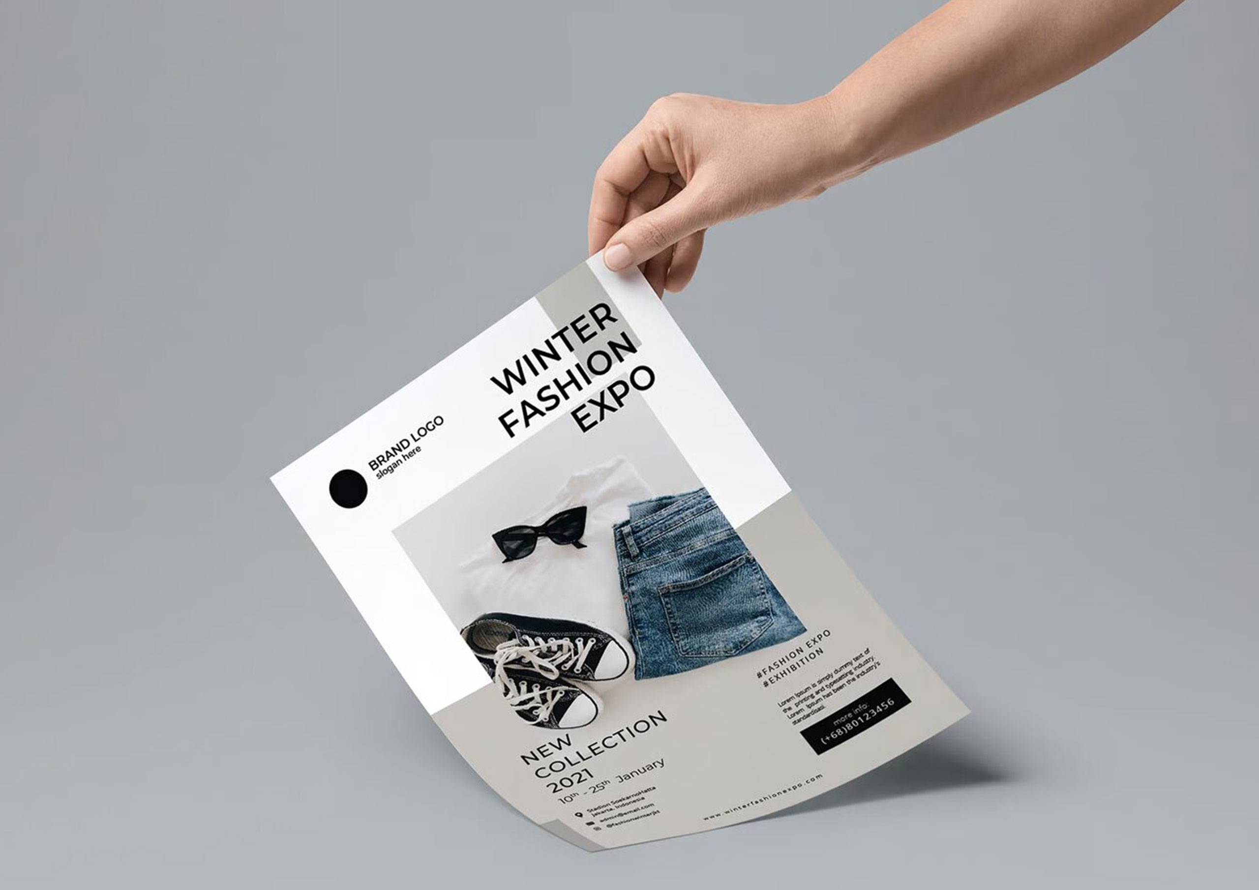 Mano sosteniendo cartel publicitario de la Winter Fashion Expo con diseño minimalista y foto de prendas, impreso por Gabella Artes Gráficas en Norte, Sevilla, ideal para promociones de eventos de moda.
